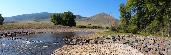 River flowing through open prairie surrounded by engineered bricks