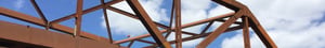 Steel beams against a blue sky with clouds